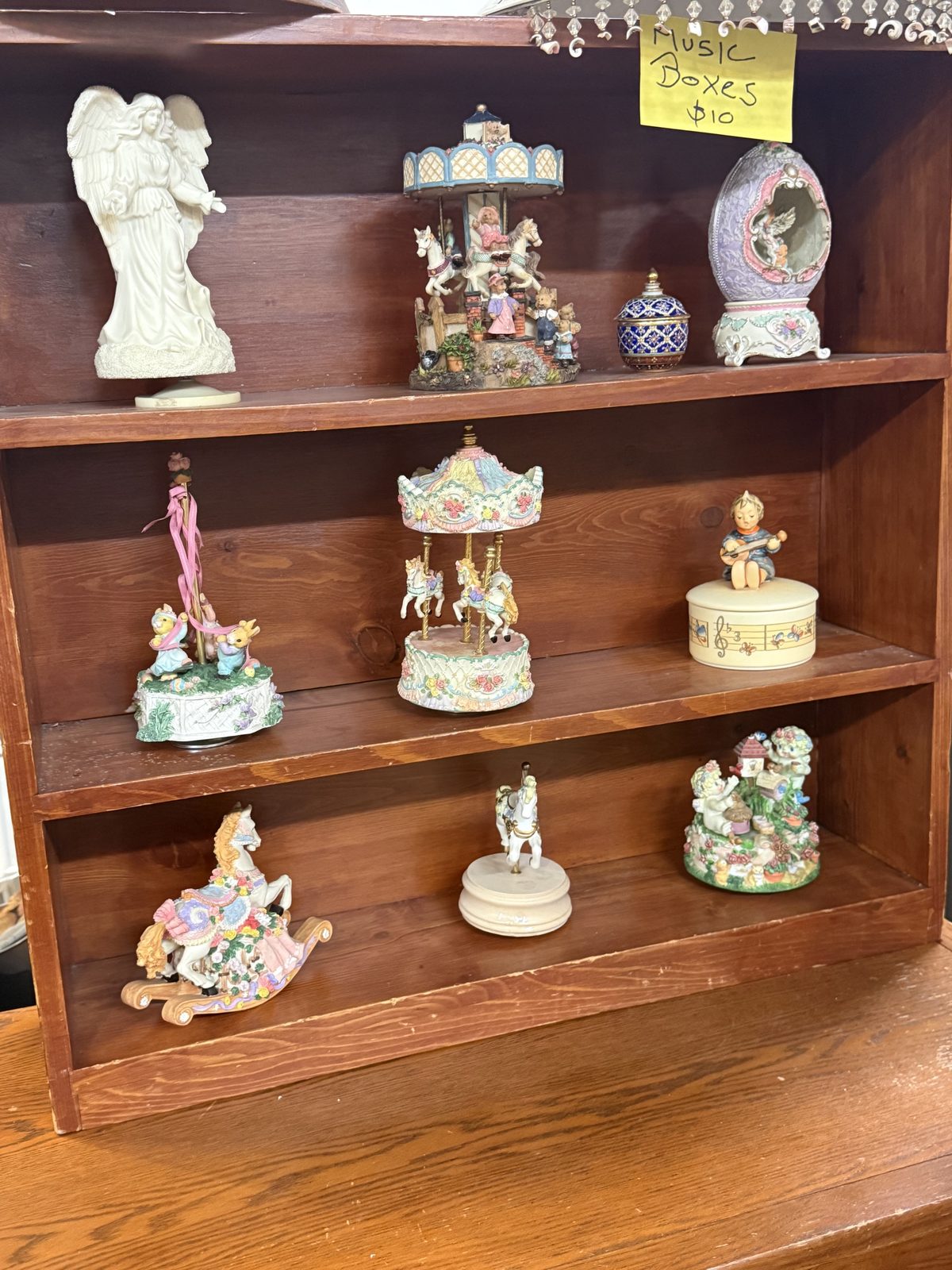 A wooden cubby of music boxes, carousels, and figurines.